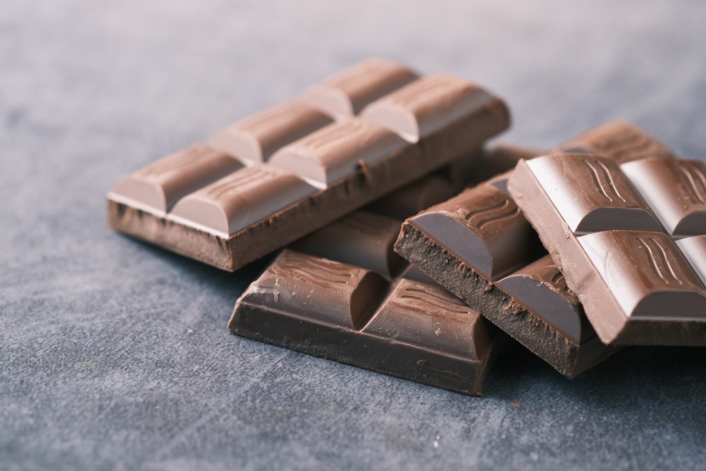 Four chocolate bars stacked on a dark surface