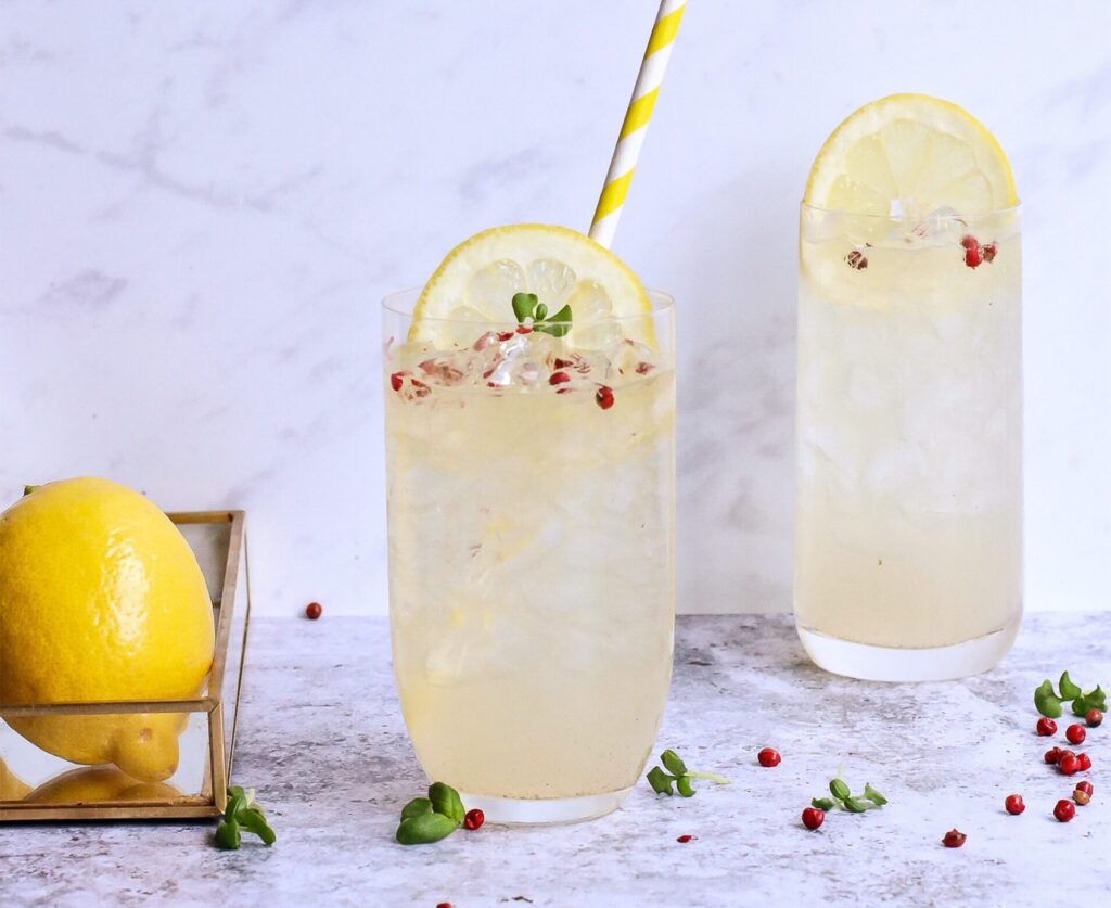 two lemon cocktails with a lemon next to it
