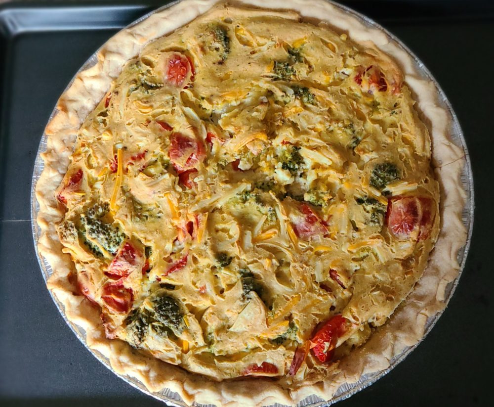 a whole vegetable quiche with a dark background