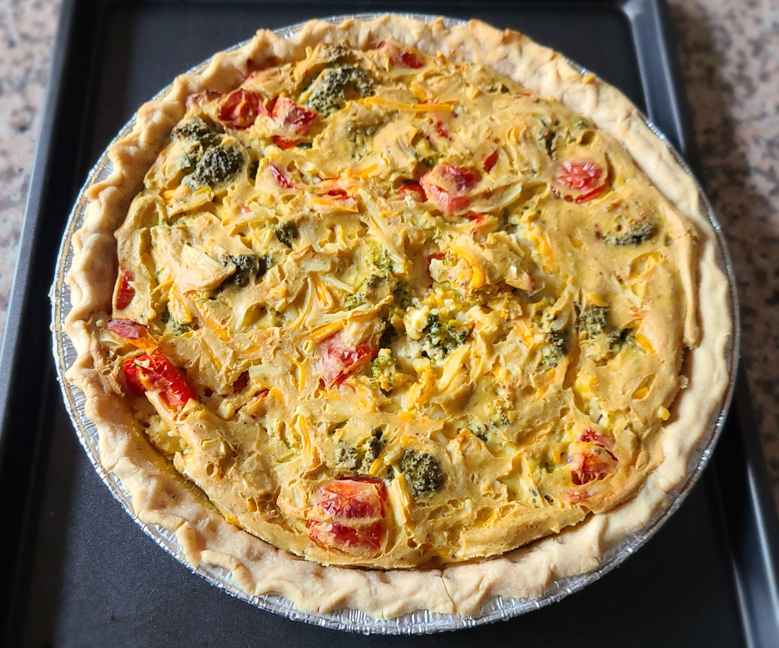 a whole vegetable quiche with a dark background