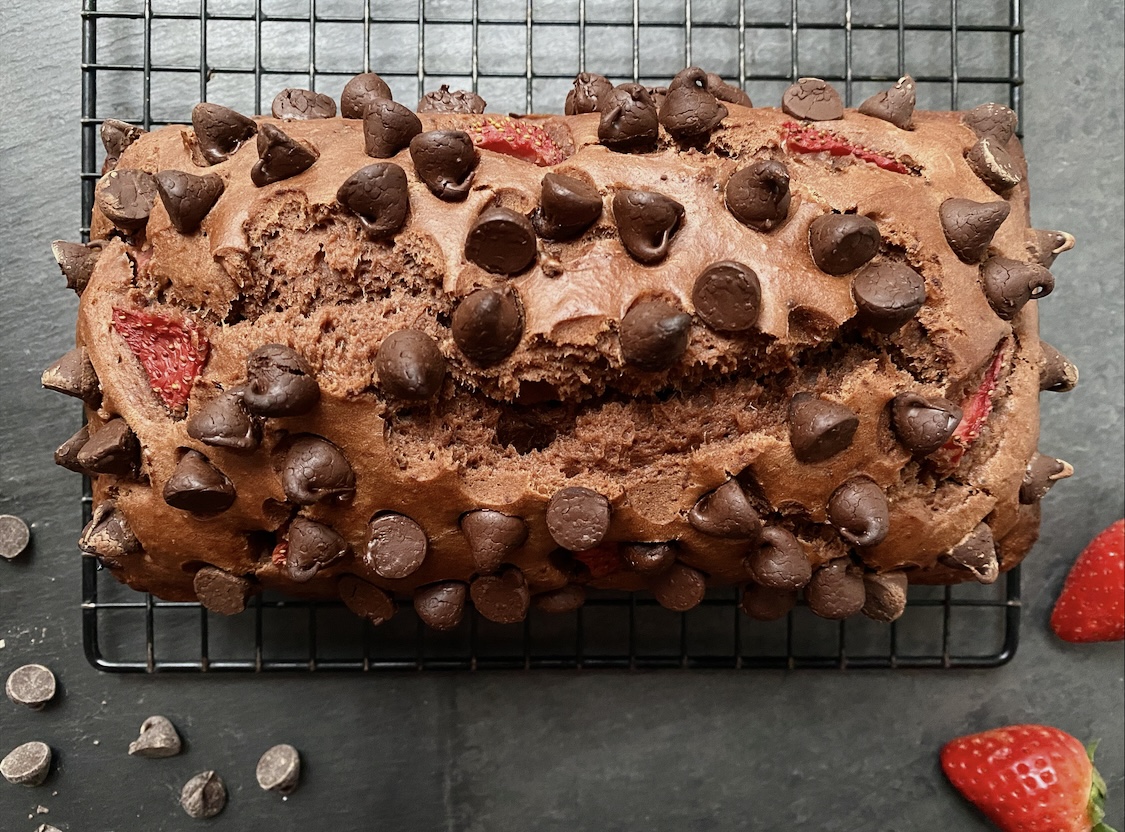 Vegan double chocolate strawberry loaf on a cooling rack against a dark gray countertop.