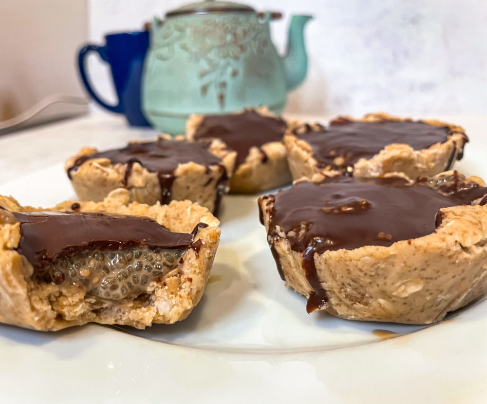 A side view of chocolate shell chia cups on a white plate.