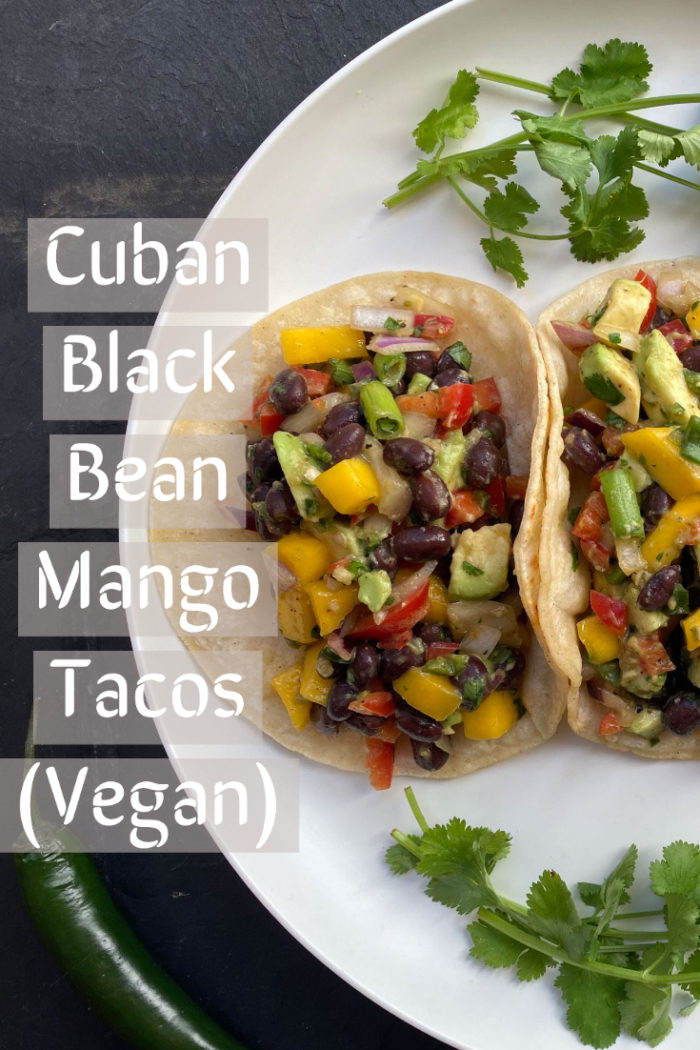 2 cuban black bean mango tacos on a white plate against a black background with the recipe title overlaid in white.