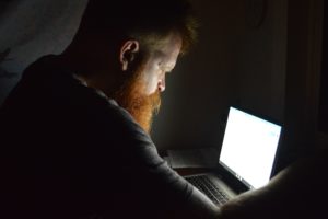 Man working at a glowing laptop in the dark.