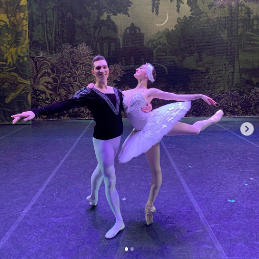 joy womack and dance partner in costume for swan lake, on a stage.