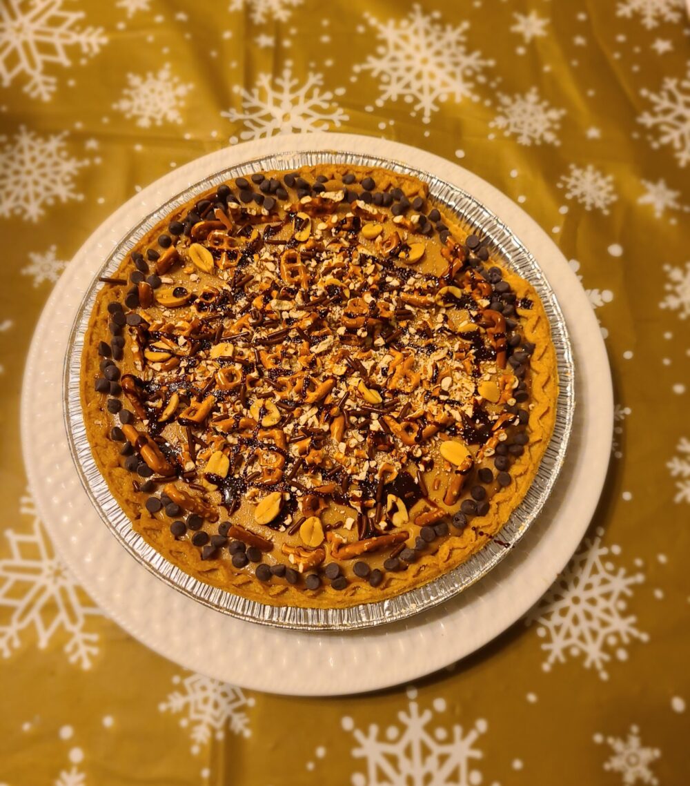 vegan chocolate peanut butter pretzel pie on a white plate against a tablecloth with snowflakes