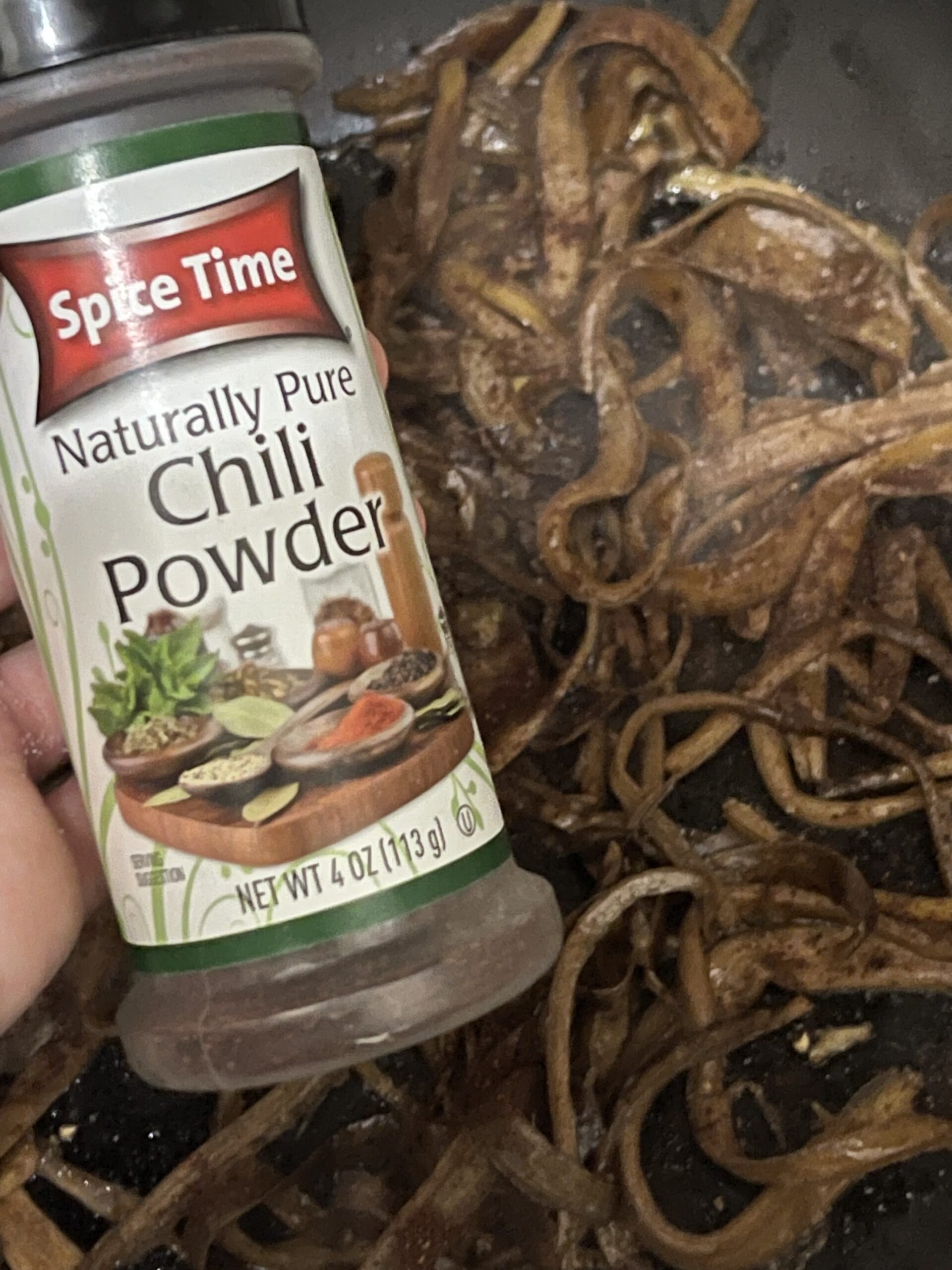 chili powder bottle next to banana peels cooking in a pan