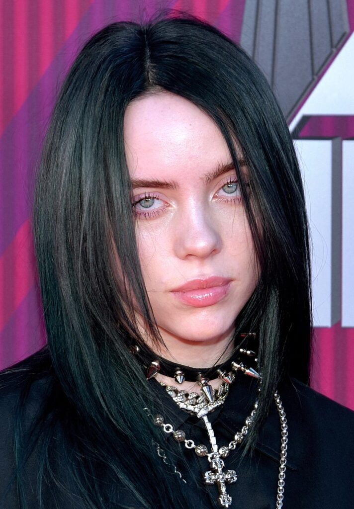Musician Billie Eilish headshot looking straight at the camera with a hint of a smile.