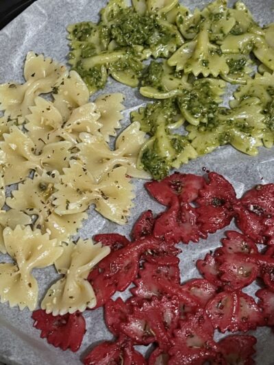 bow-shaped cooked pasta tossed in olive oil, beet root powder, and pesto