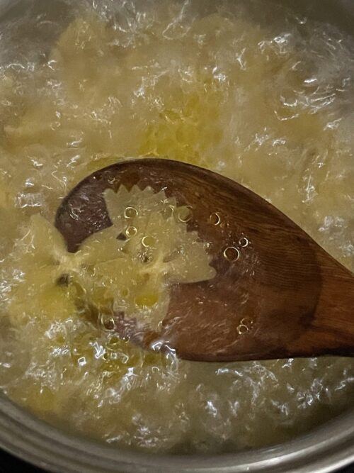 boiling pasta in water and stirring with a wooden spoon