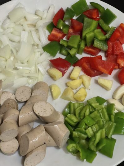 onions, bell peppers, garlic, vegan sausage, chopped and on a white plate