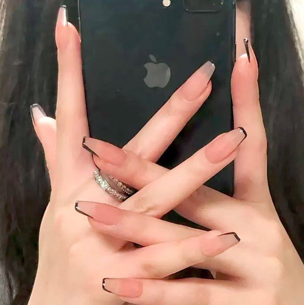 Long and slightly square-edged nails painted pink and edged around with dark gray. The hands are holding a black iphone. 