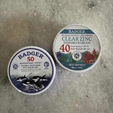 Badger brand zinc oxide sunscreens in tins on a marble table. 