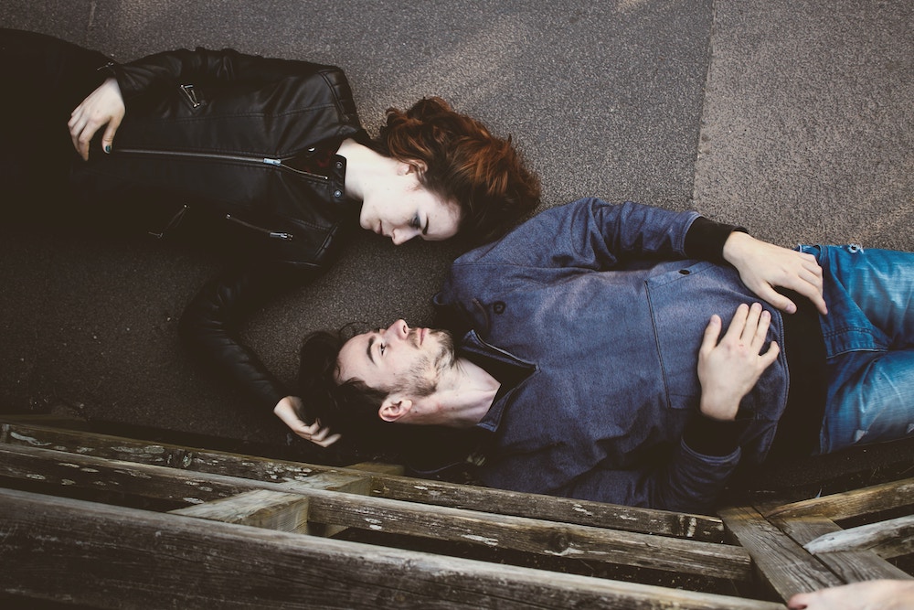 a bird's eye view of a woman and a man lying don on the floor and looking into each other's eyes.