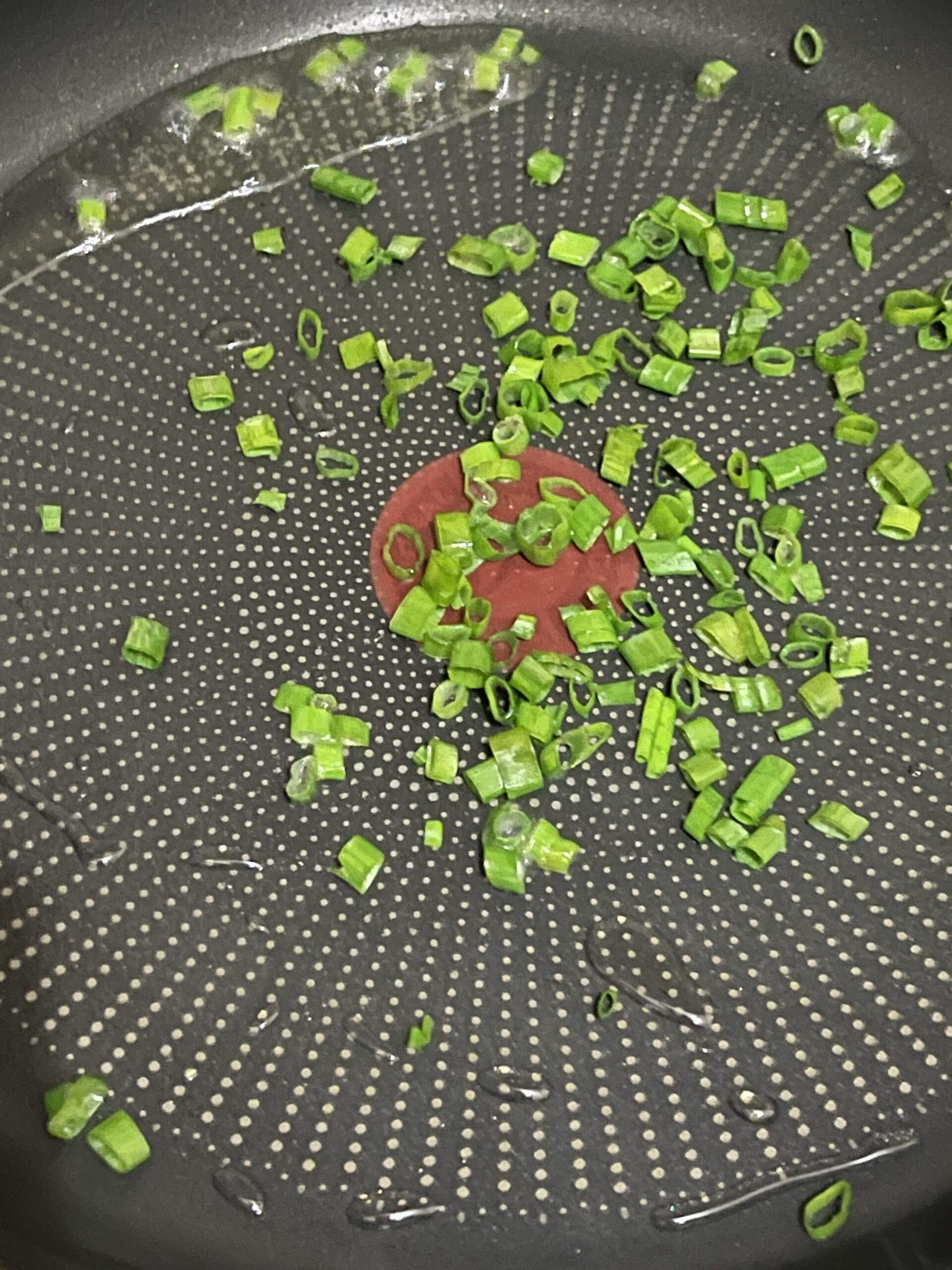 frying green onions in a pan.