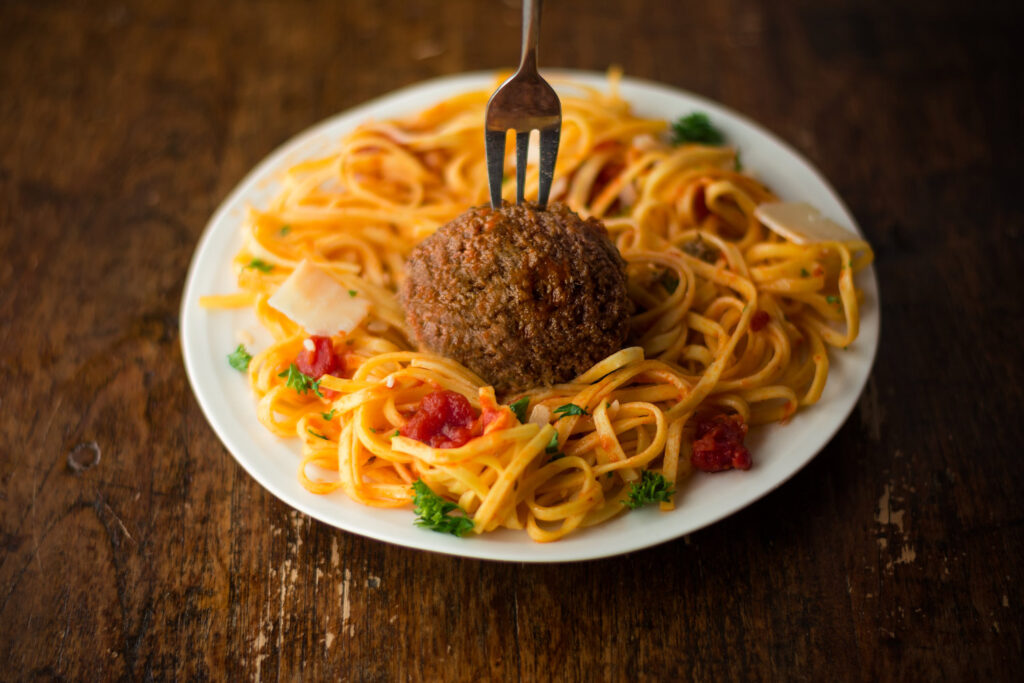 Spaghetti_With_A_Cultivated_Lab_Grown_Meatball_On_A_Wooden_Table_With_A_Silver_Fork