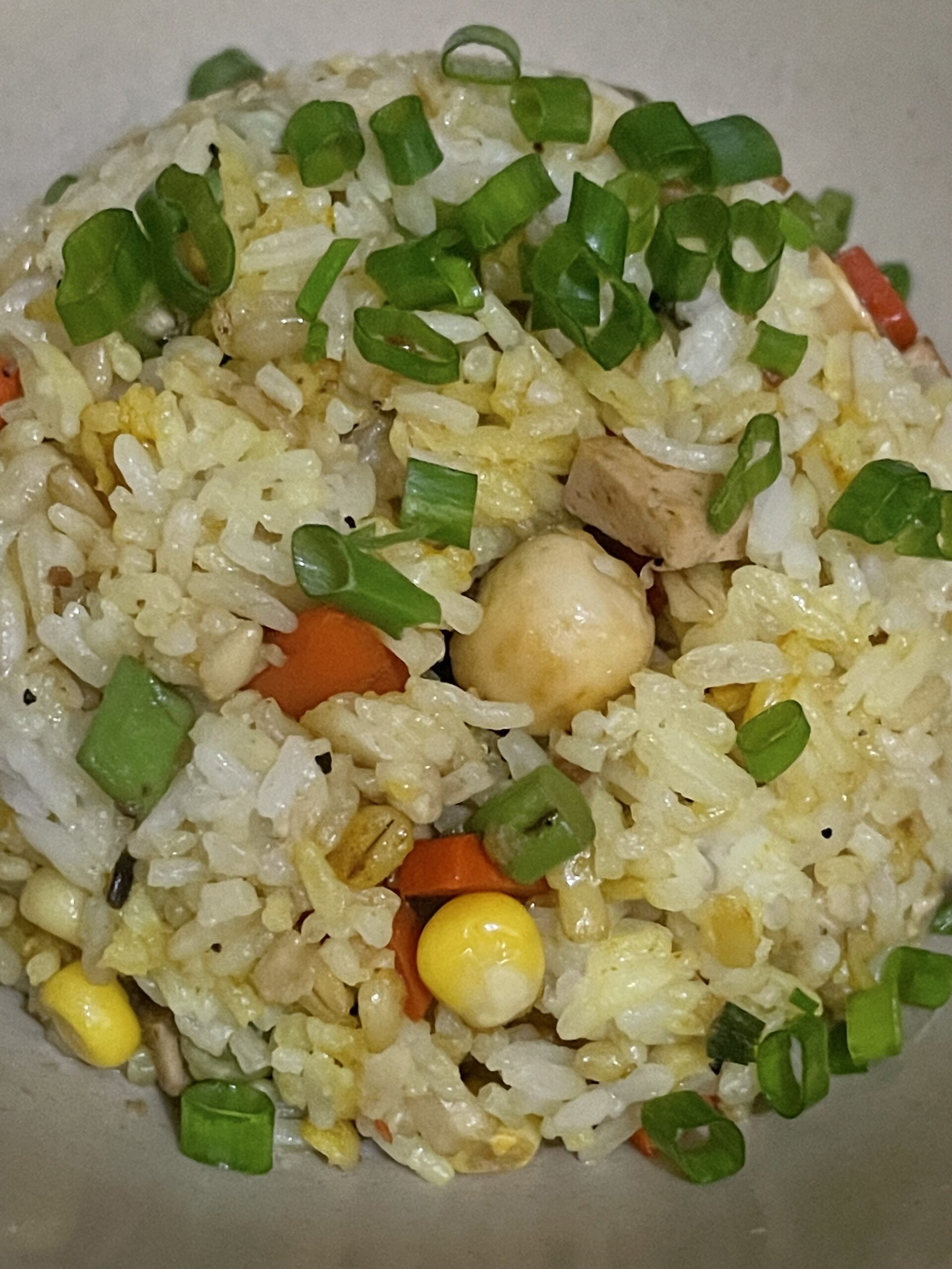 lotus seed fried rice garnished with chopped green onions on a plate.