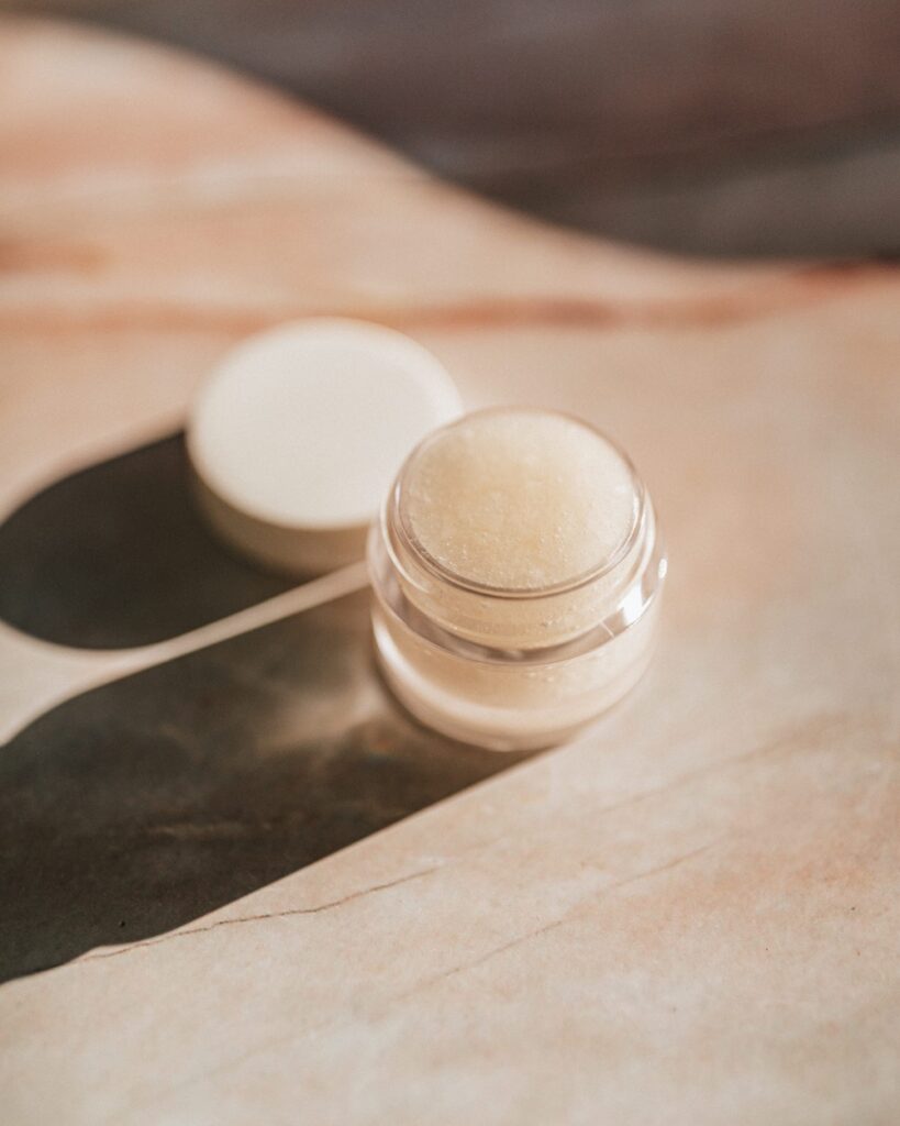 a jar of cream-colored balm on a neutral background.