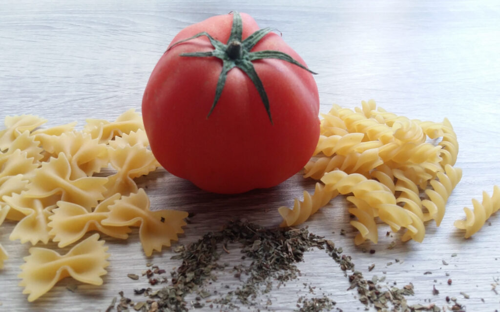 Dried_Ziti_And_Farfalle_Pasta_With_Red_Tomato_And_Basil_And_A_Grey_Background