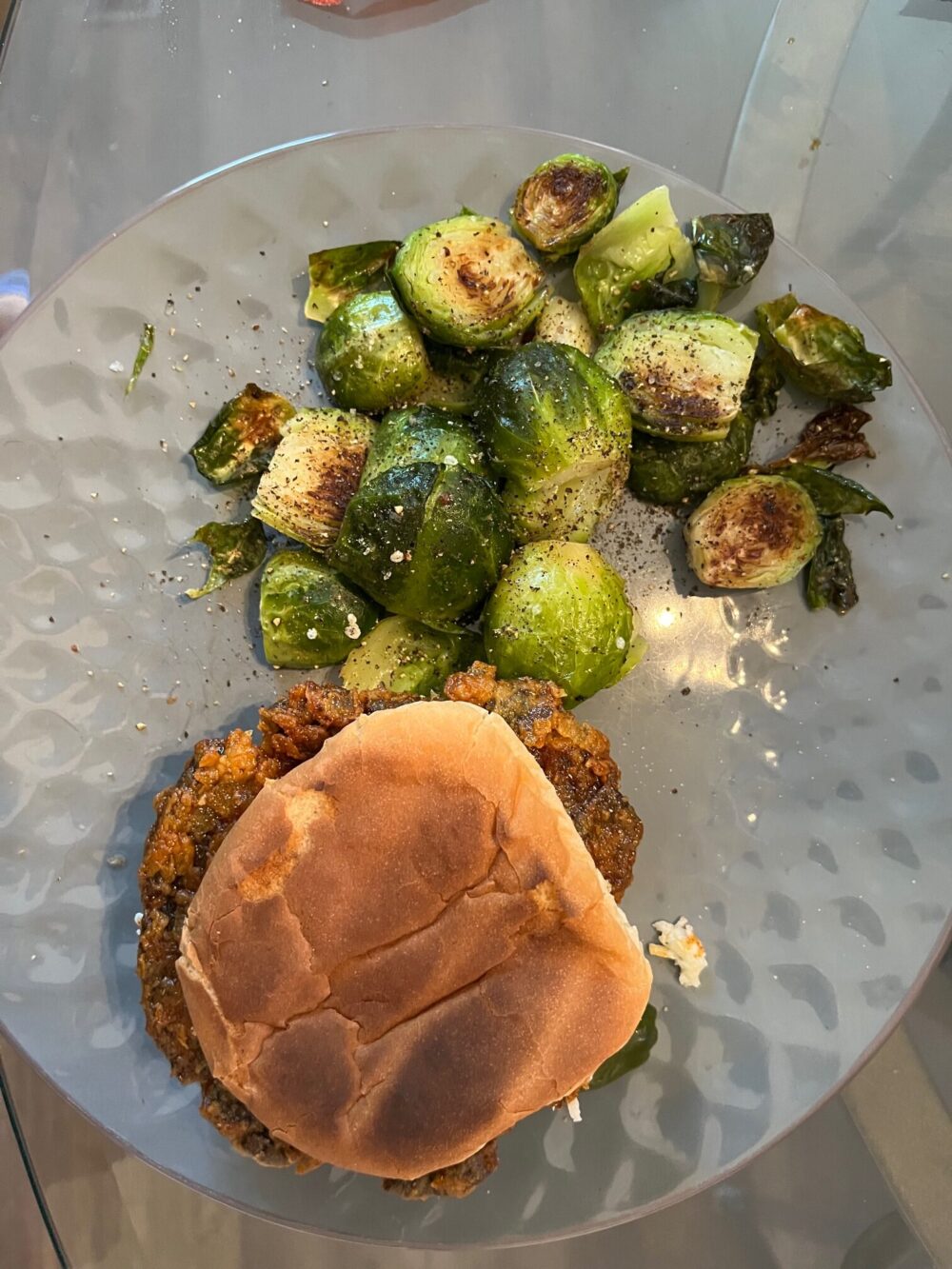 fried portobello sandwich with bun and roasted brussels sprouts on a gray plate