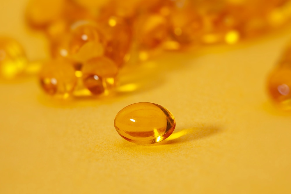 Clear golden capsules against an orange background.