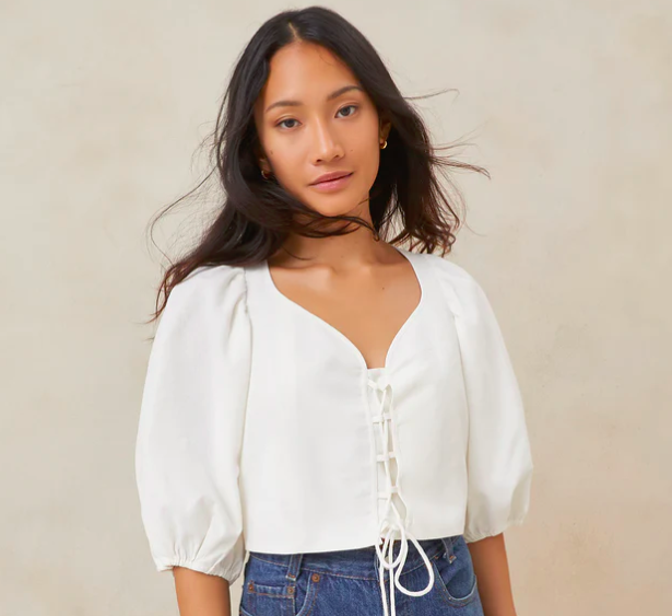 a woman wearing a white lace up blouse by Loeffler Randall