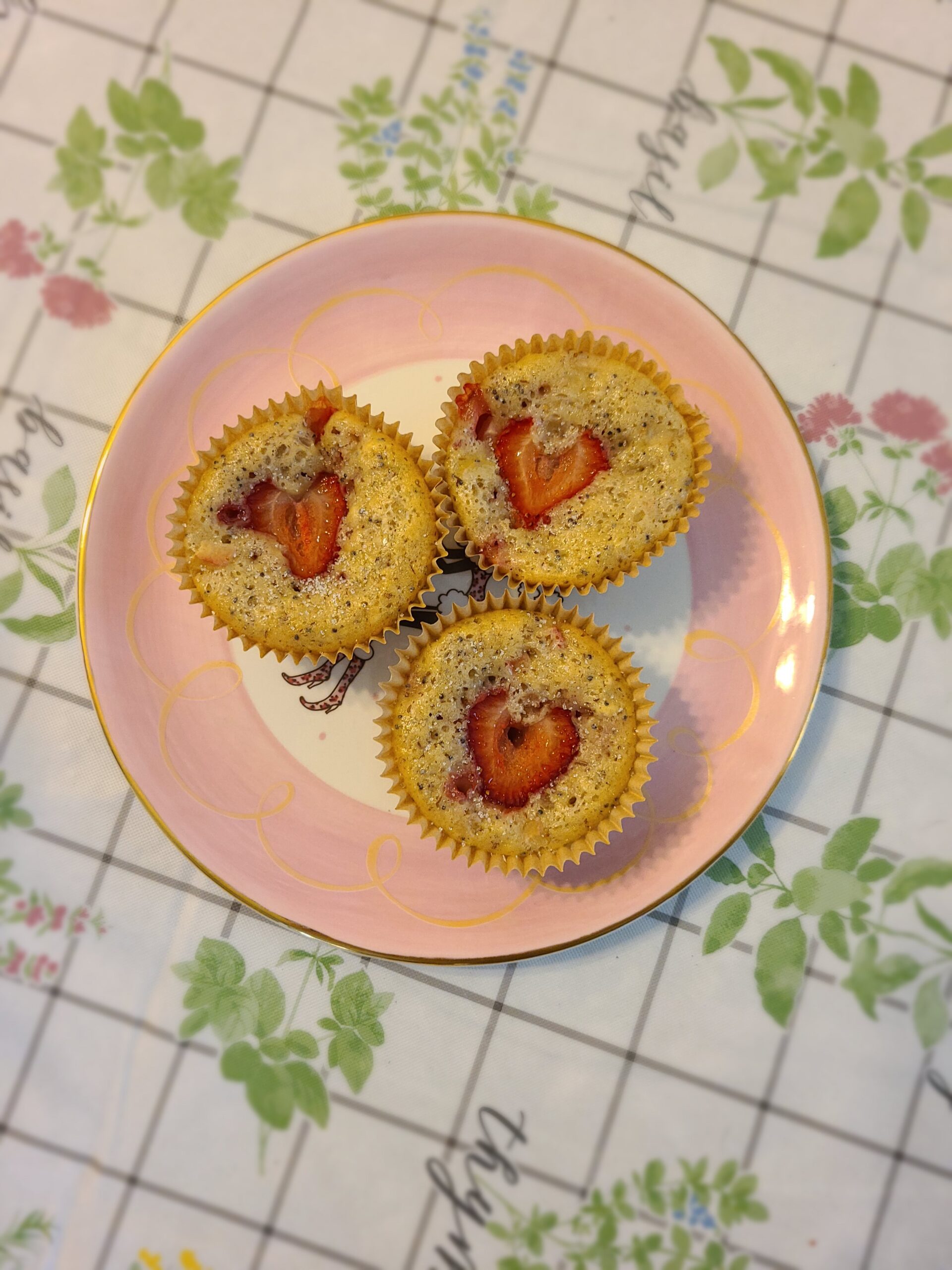three vegan strawberry rhubarb muffins on a pink plate