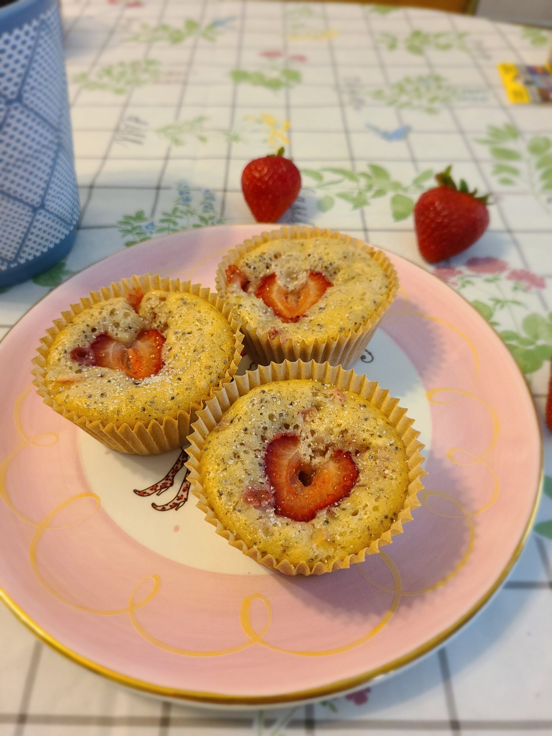 three vegan strawberry rhubarb muffins on a pink plate