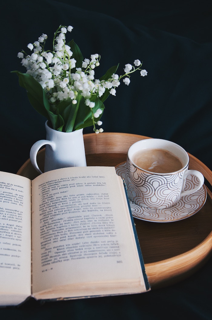 a book open on a table with a mug of coffee next to it