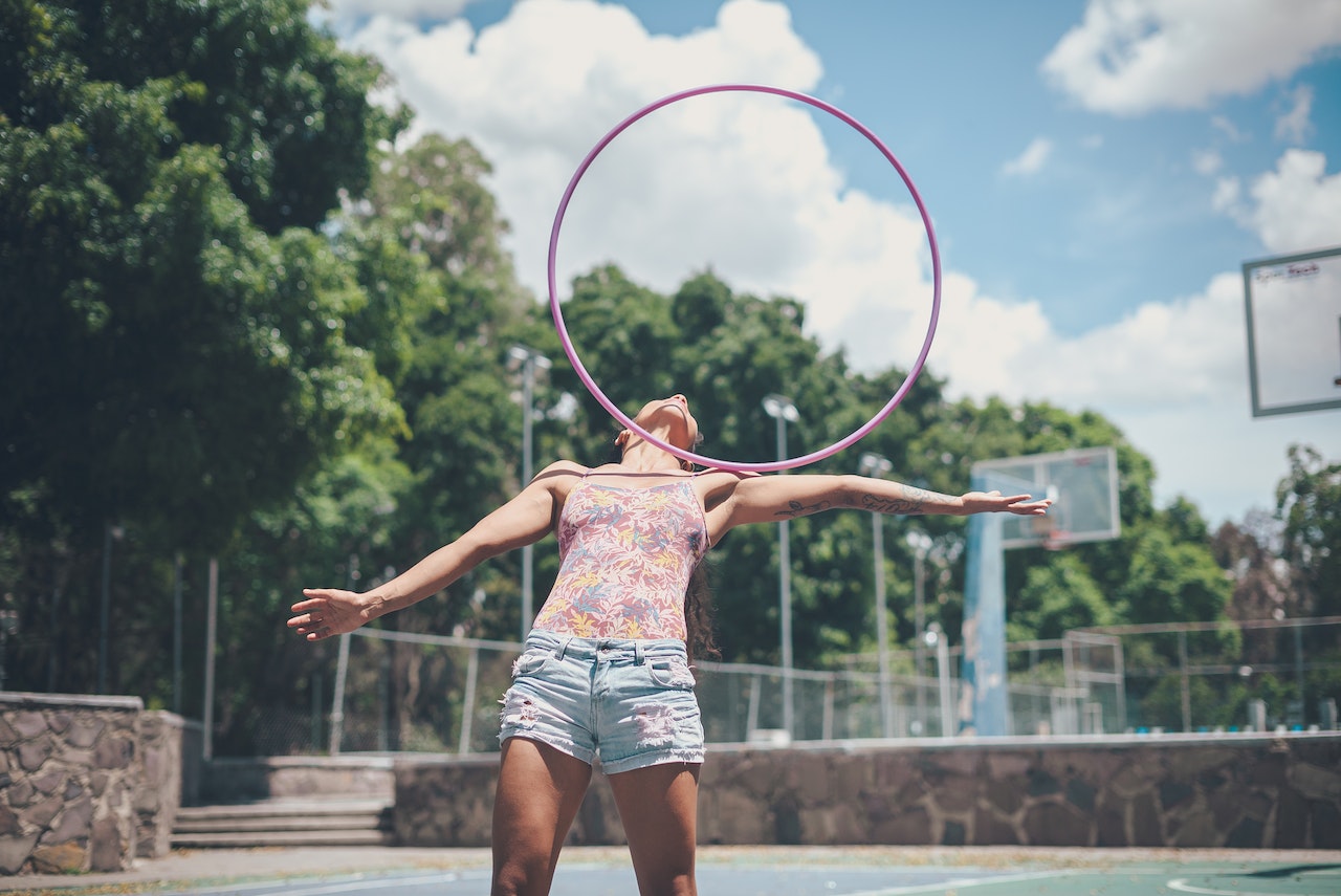 a woman balancing a hula hoop on her shoulder in a park