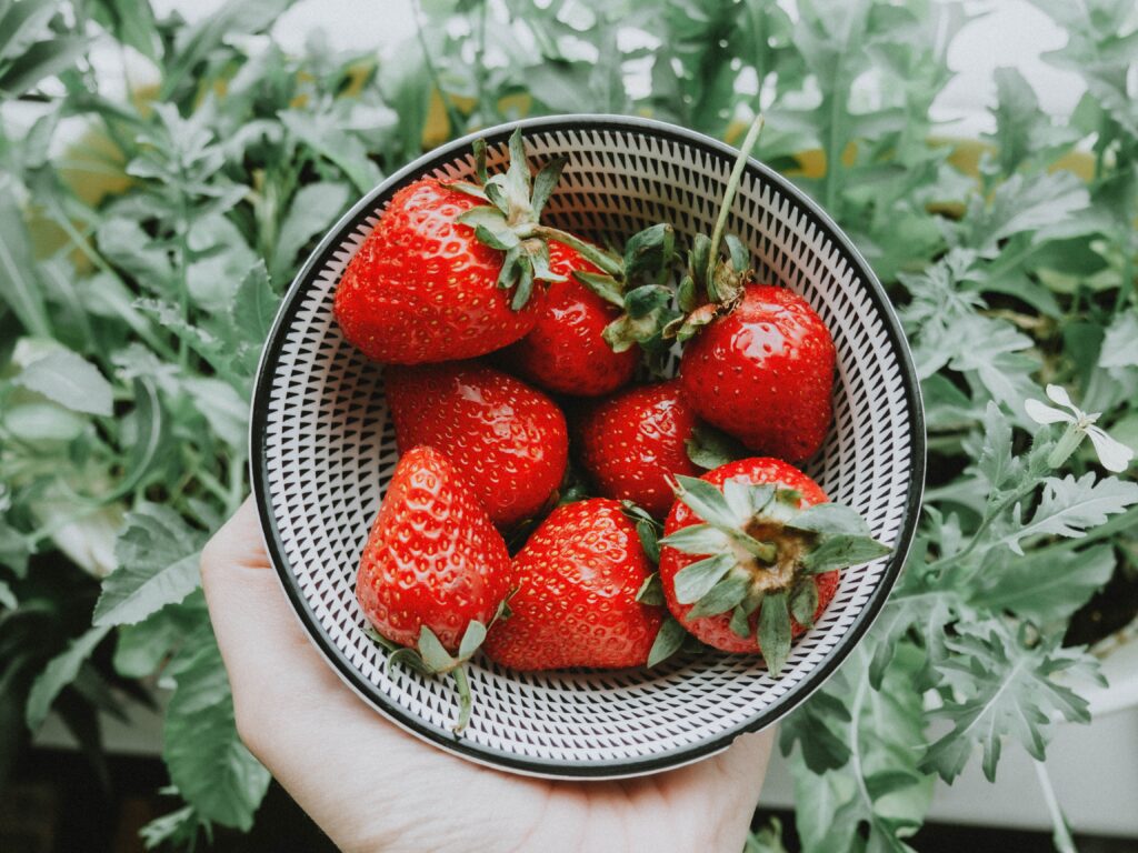 bowl of strawberries with tops. Use strawberry tops to help minimize food waste